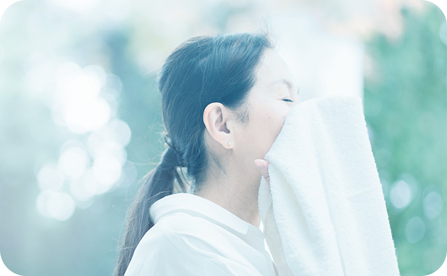 写真：タオルで顔を覆う女性